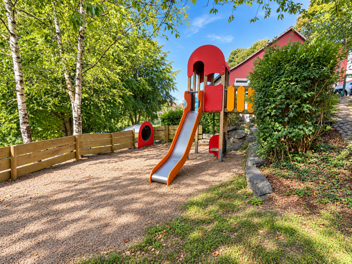 Roter Spielturm mit Rutsche im Garten